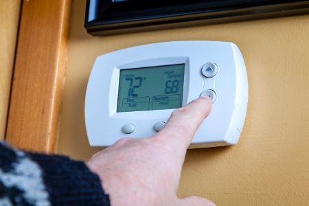 Person adjusting temperature on thermostat