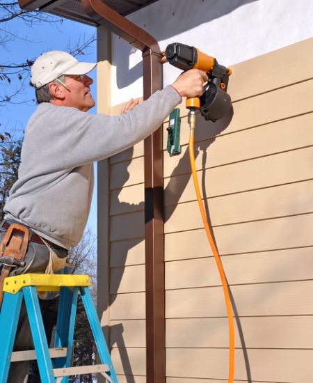 Man applying siding to a house